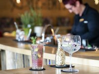 Man sieht zwei Cocktails an der Bar